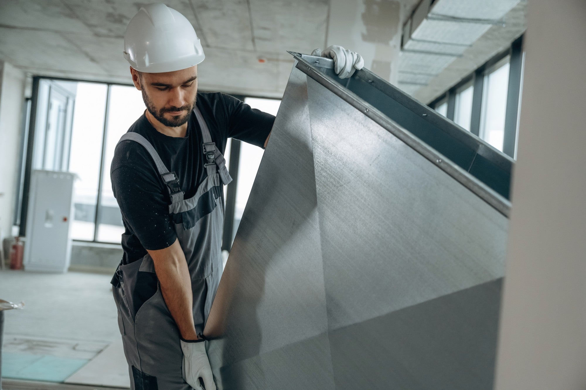 Construction worker moving commercial HVAC duct.
