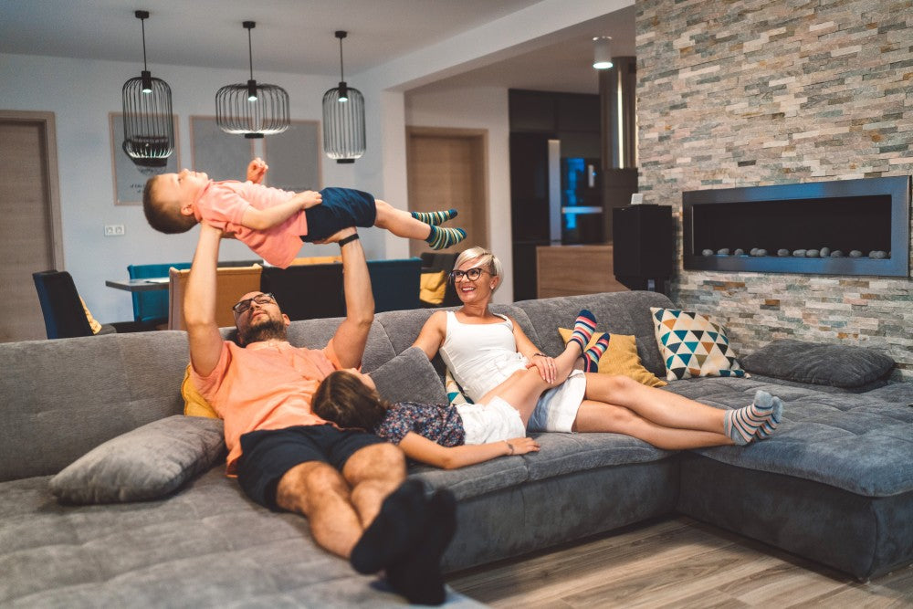 Family relaxing on sofa while dad lifts small boy.