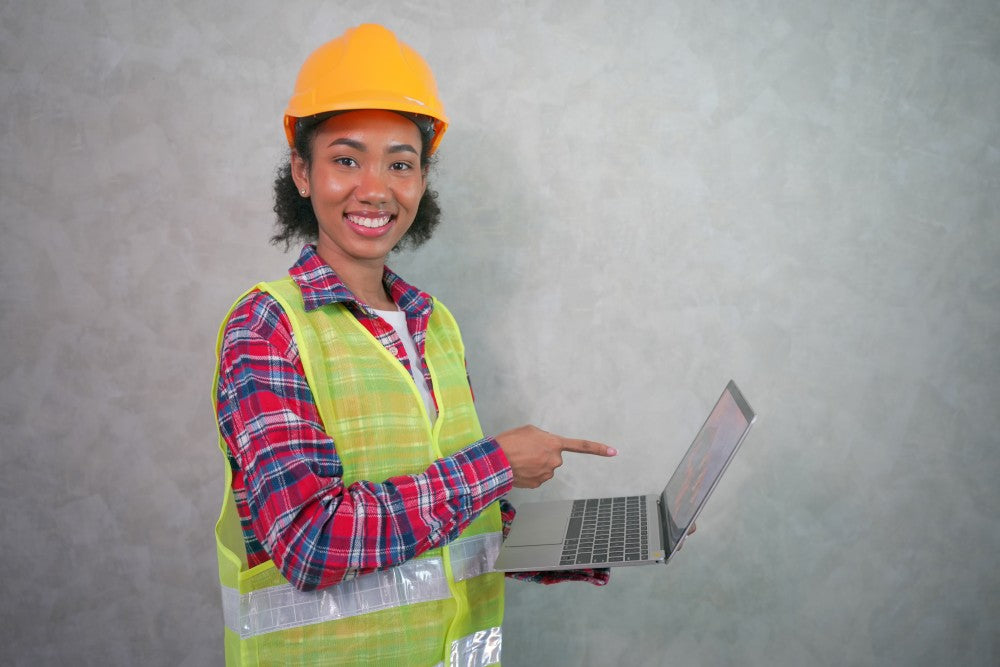 Female construction worker pointing at notebook computer.