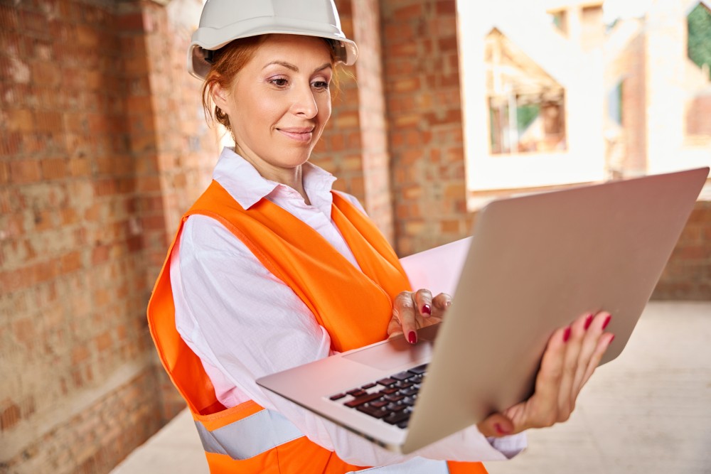 Female construction engineer using laptop to order HVAC parts online.