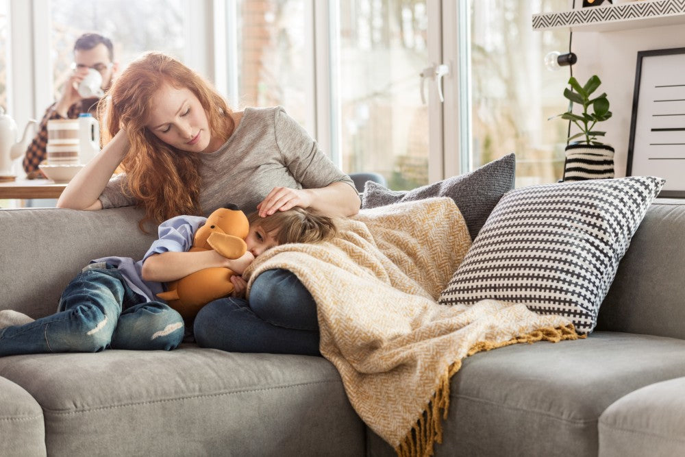 Mother with blanket on her lap taking care of child.