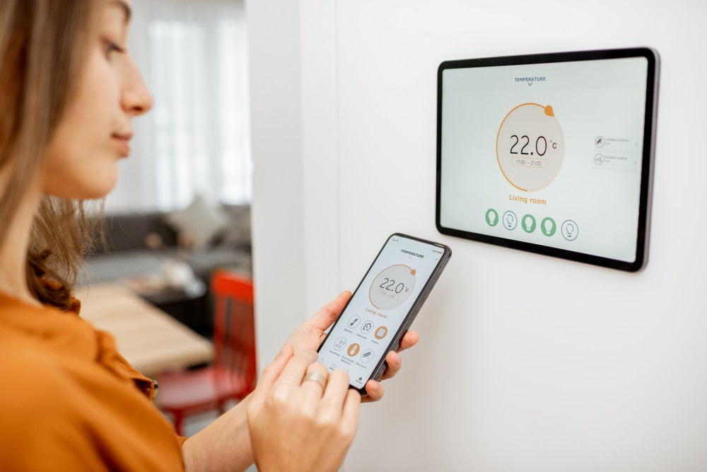 Woman adjusting the cooling temperature on a digital thermostat.